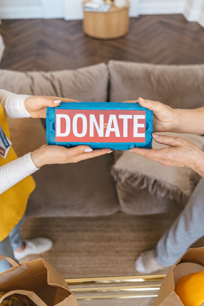 pexels photo 7345451 7345451 Two people exchanging a donation box indoors, symbolizing generosity and charity.